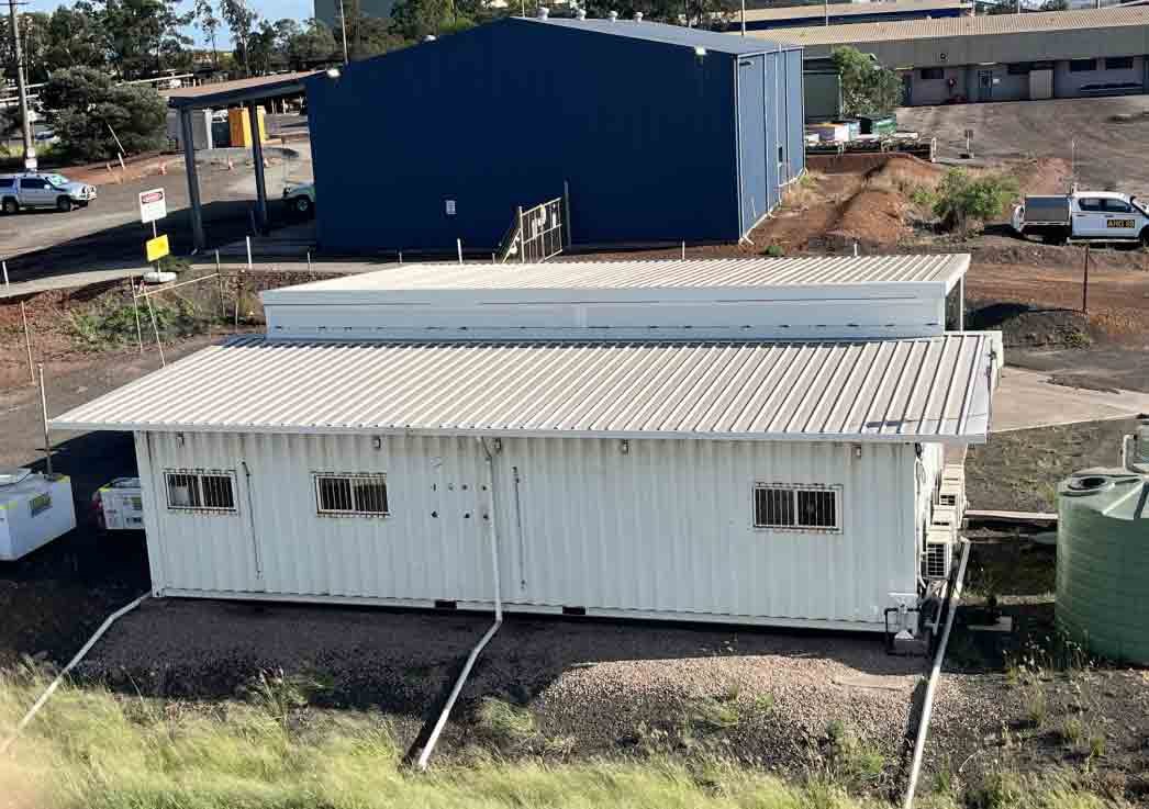 Construction site with blue warehouse and container van office - MM & IM Local Infrastructure Mangement Specialist 